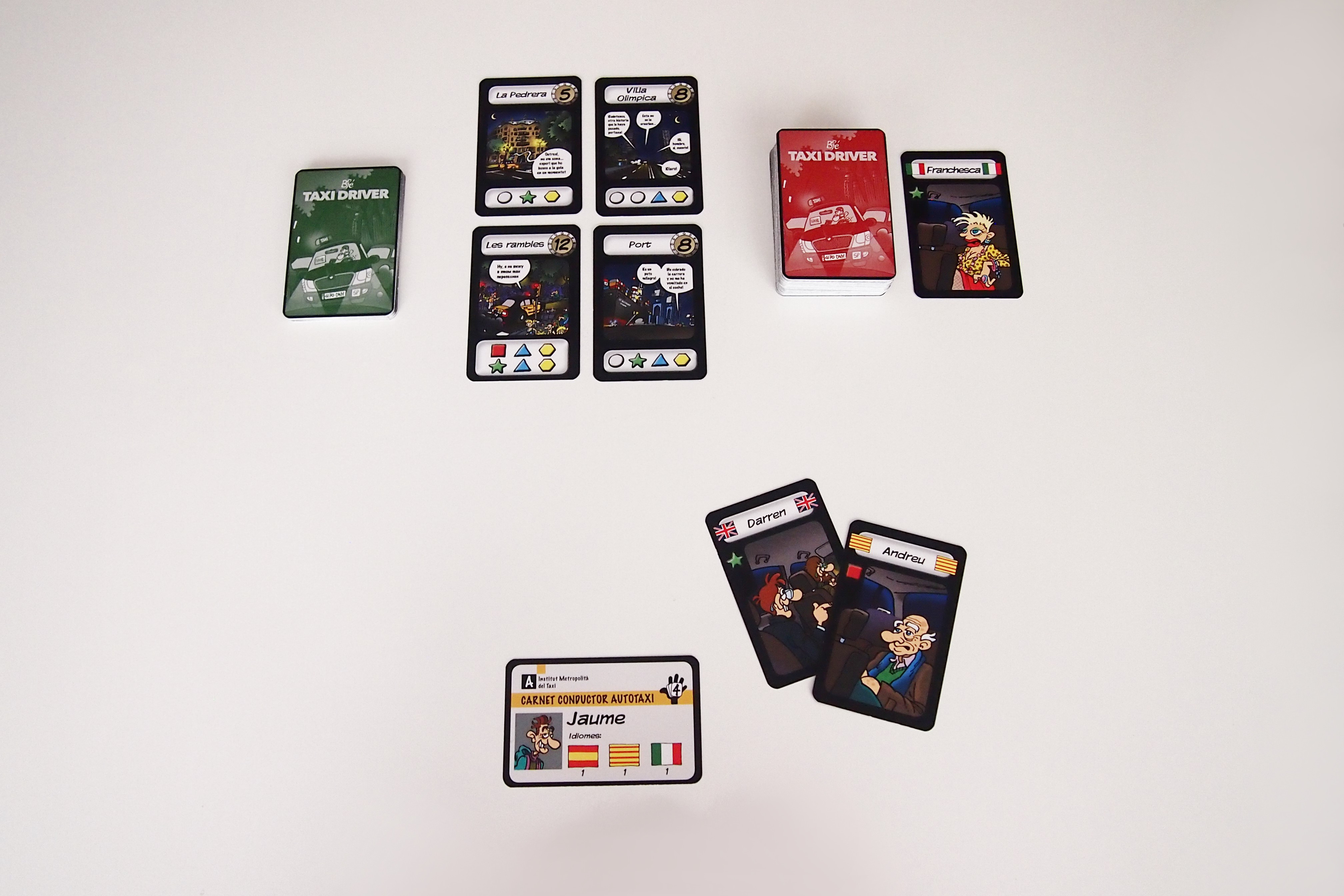 Disposición de los componentes antes de empezar la partida. Cada jugador recibe una carta de taxista (cara A) y dos cartas de pasajero. 